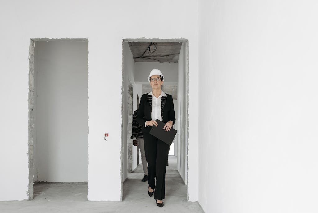 Businesswoman in hard hat walking through construction site, holding a folder.