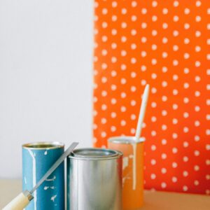 Colorful paint cans against a polka dot wallpaper ready for a home renovation.
